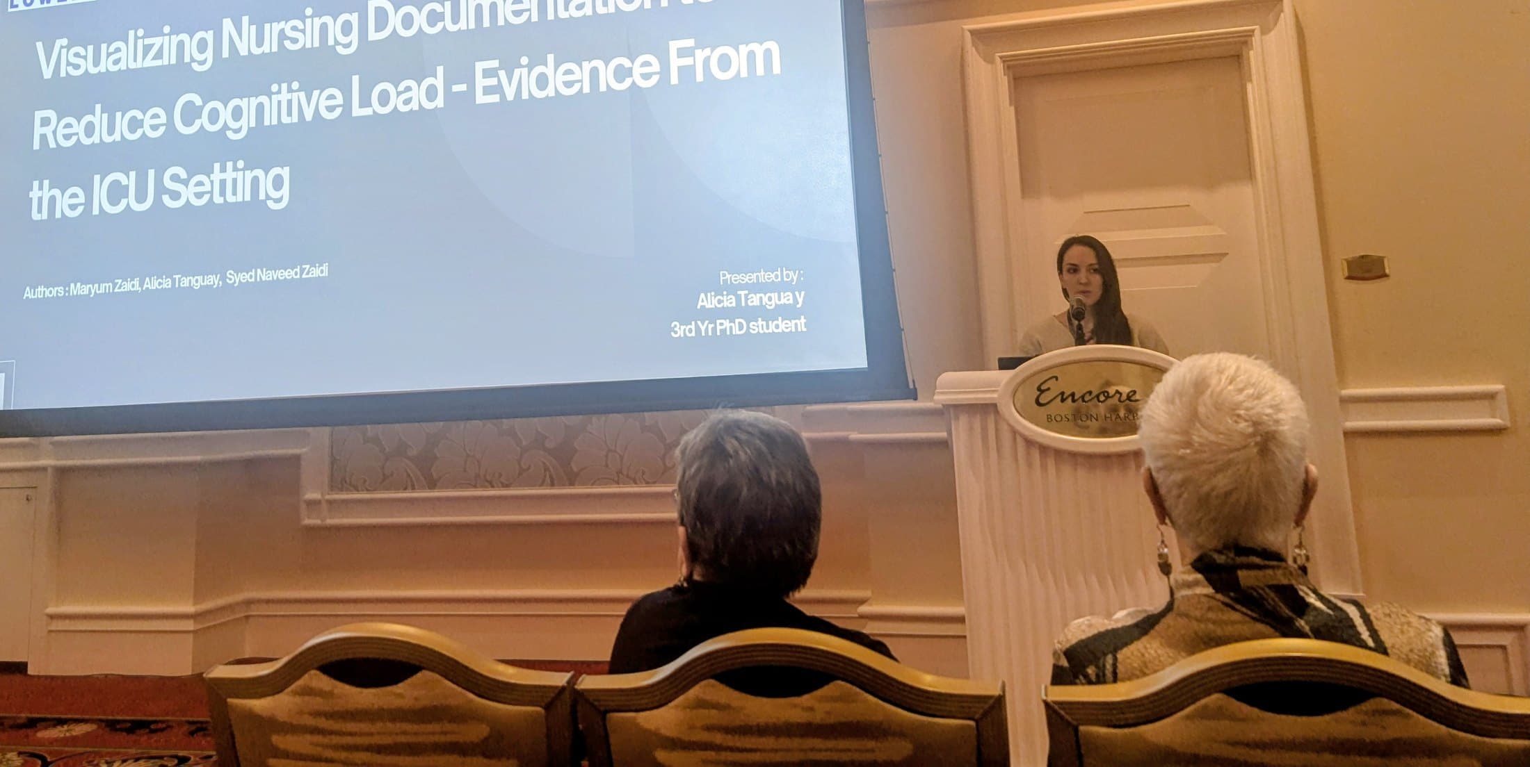 Alicia Tanguay presenting the ICU study at a podium beside the title slide
